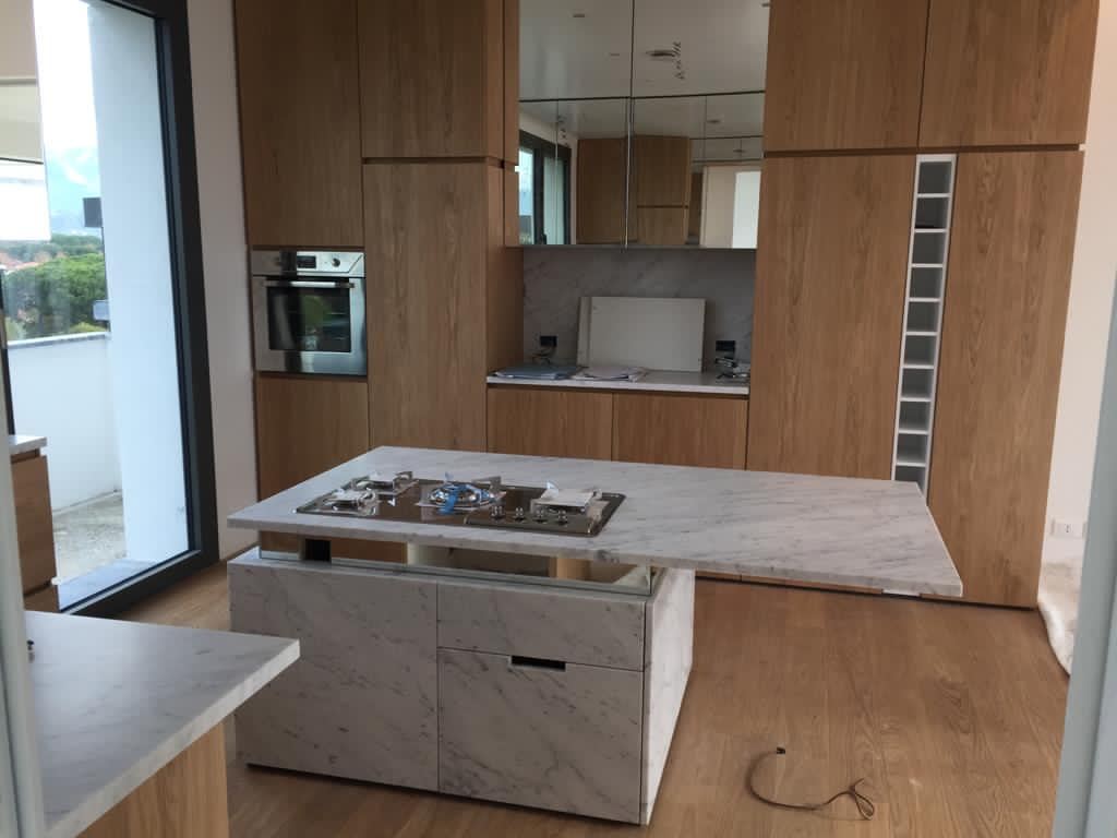 L'isola in marmo con i fuochi e la parete attrezzata in rovere con il forno