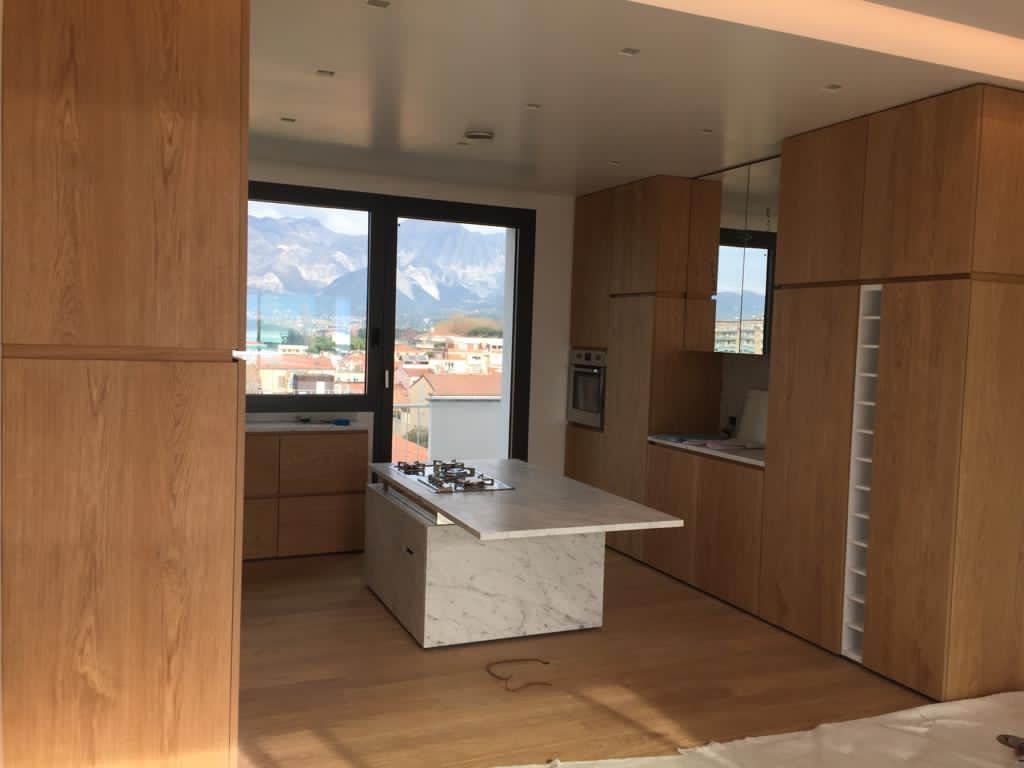 La cucina vista dal soggiorno, fra le colonne in rovere, con le montagne oltre la vetrata