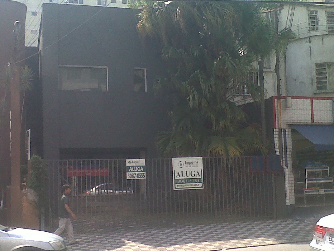 Fotografia del 2012: l'edificio sfitto, una scatola scura di due piani dietro una cancellata, con due cartelli ALUGA appesi