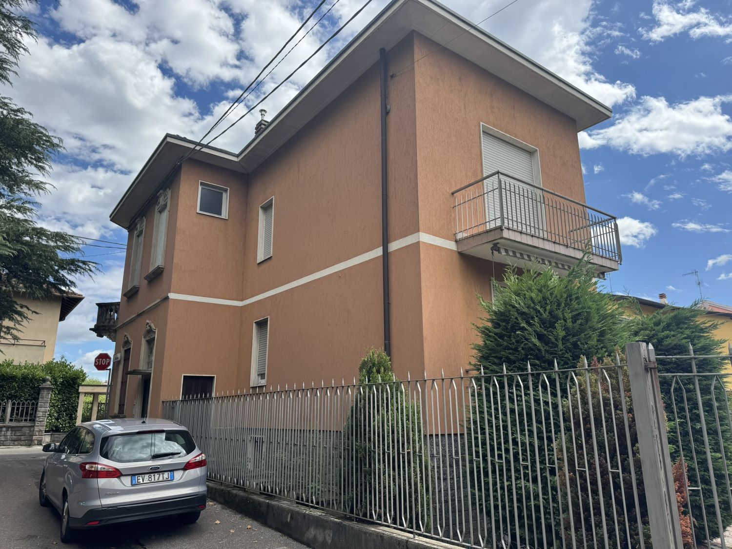 La villa d'epoca vista dalla strada: due piani, intonaco color terra, balconi in ferro e cancellata