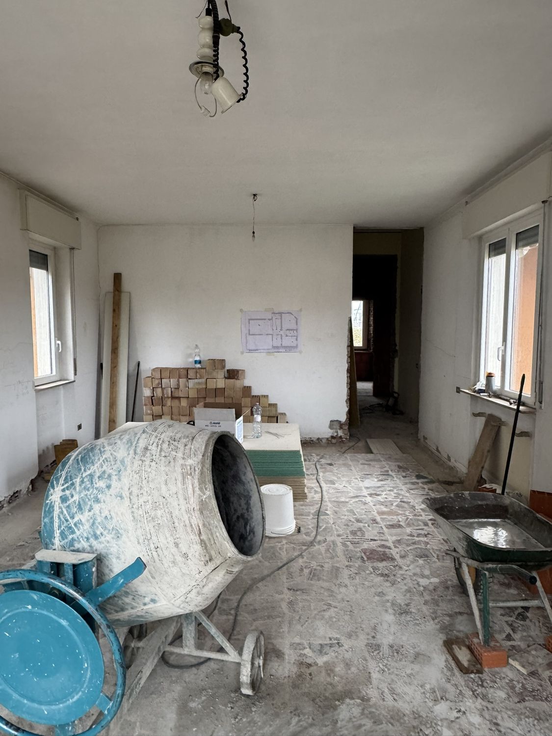 Cantiere: la betoniera in mezzo alla stanza, i sacchi di malta e il pavimento vecchio