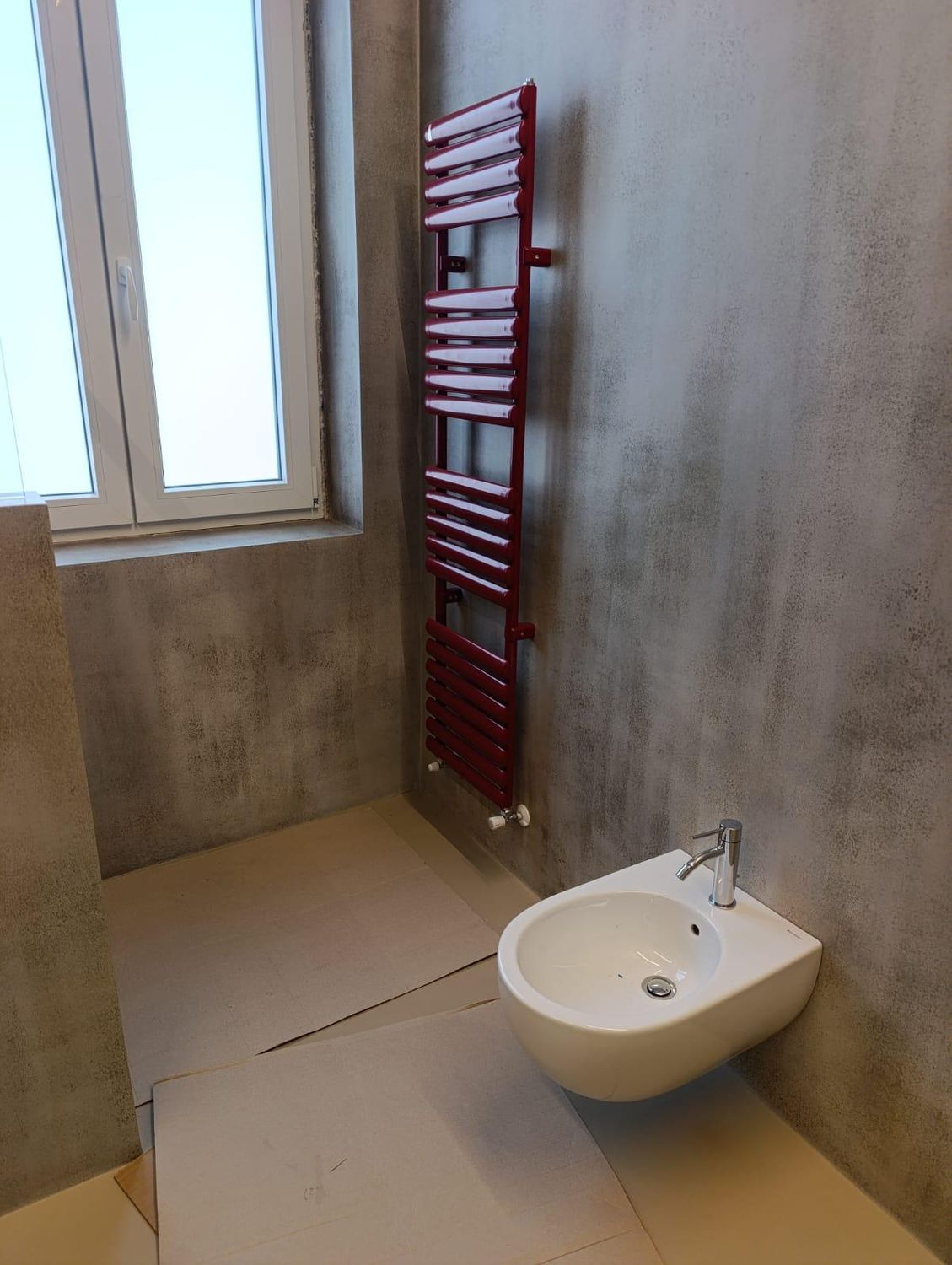 Il bidet sospeso nel bagno padronale, con il termoarredo rosso a parete e la finestra a vetro satinato accanto