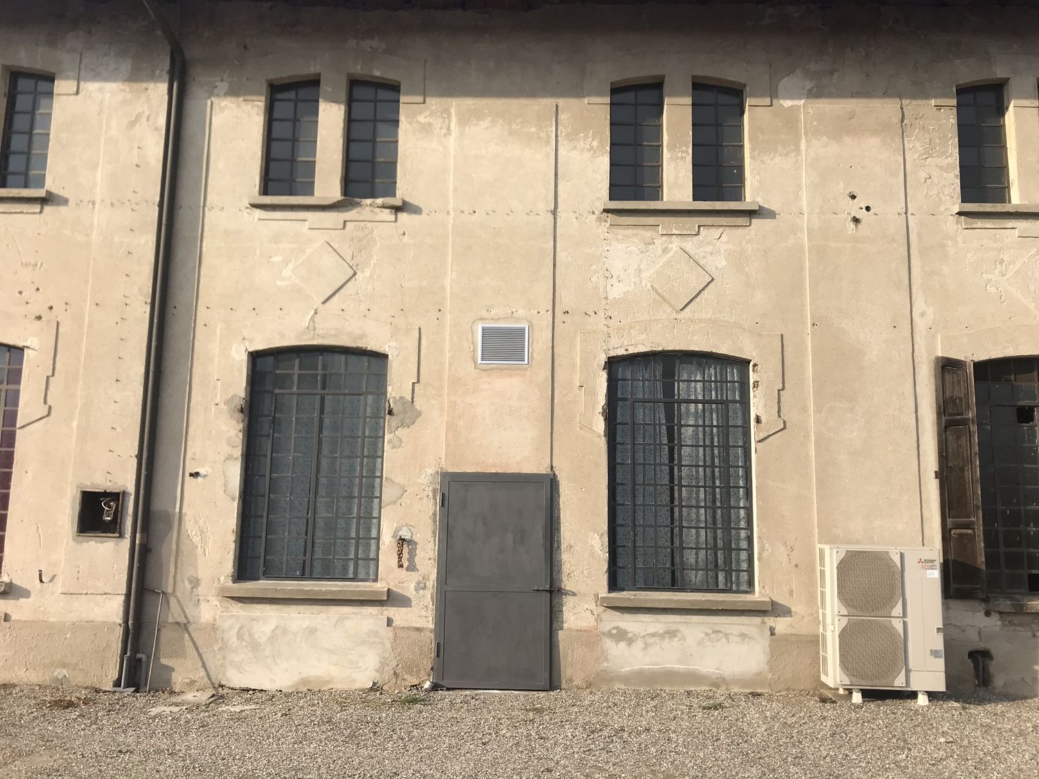 Il casolare prima: il fronte lungo con l'intonaco scrostato e le finestre ad arco chiuse da ante scure