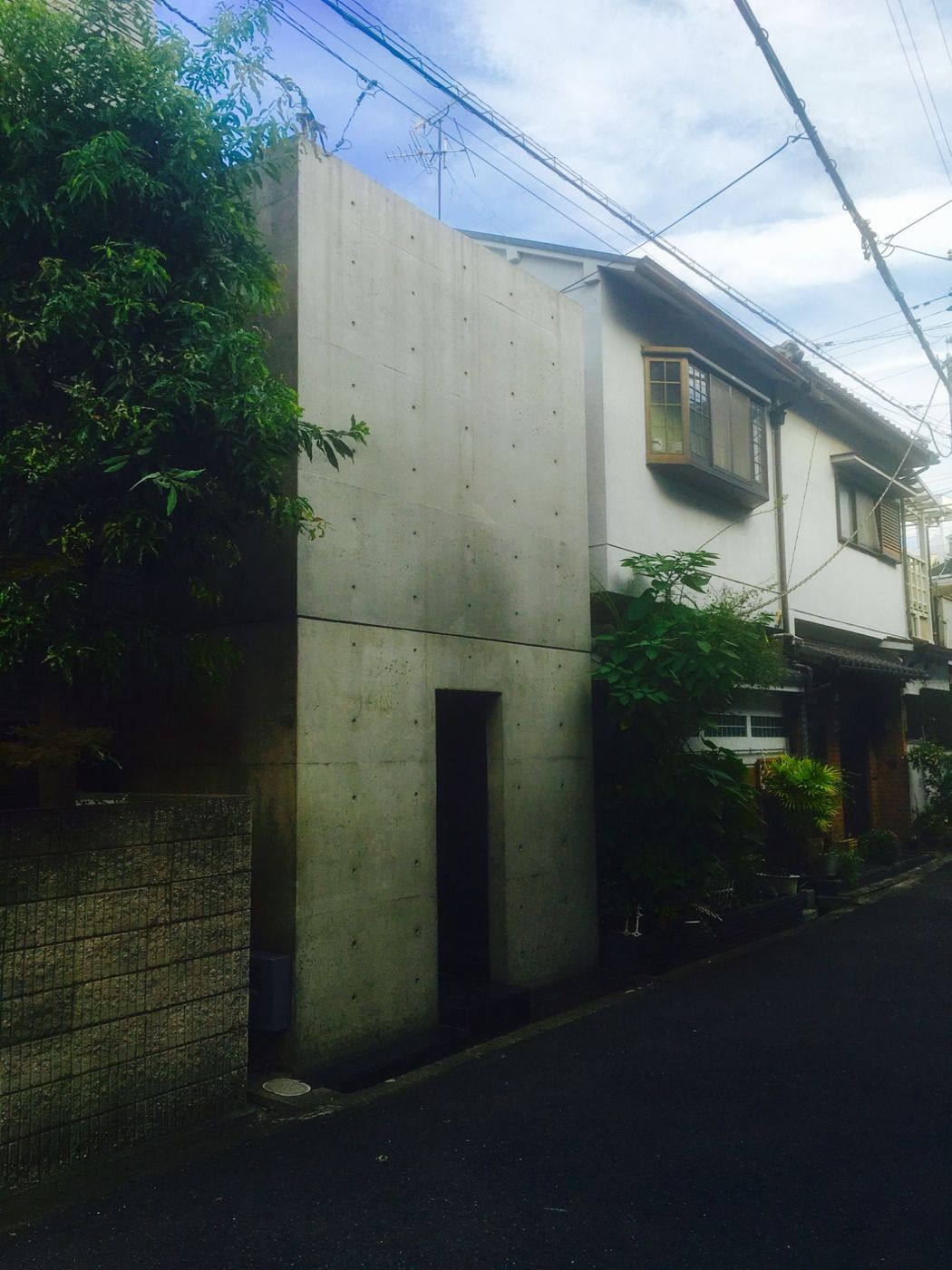 La Row House di Tadao Ando a Sumiyoshi: un muro di cemento cieco con una stretta fessura d'ingresso, incastrato fra le case tradizionali di una via stretta di Osaka
