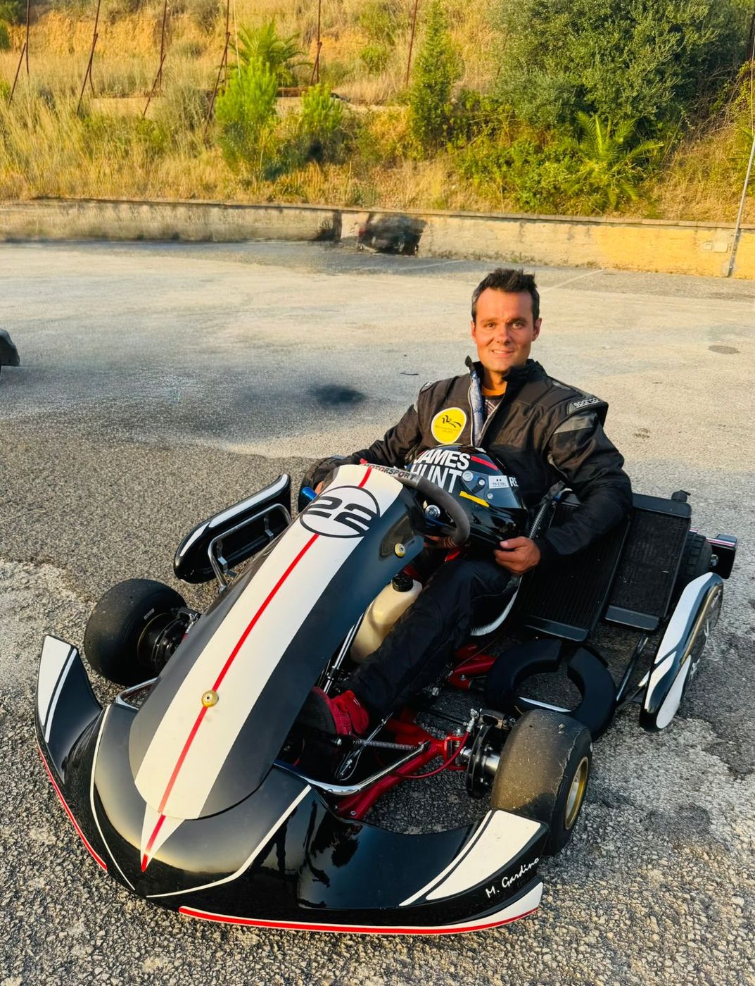 Matteo Gardino seduto nel suo kart con il casco in mano: carrozzeria nera e bianca con una riga rossa continua, il numero 22 sul cofano e il nome sulla fiancata