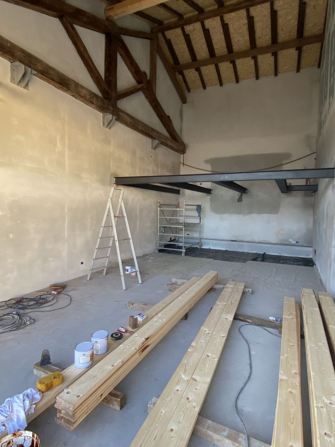 Fotografia di cantiere del box, dicembre 2023: il soppalco in ferro montato e le travi in legno a terra