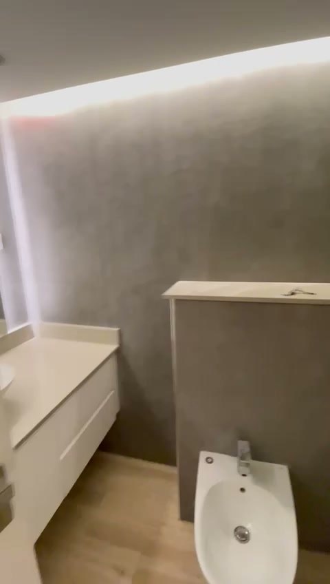 Il mobile lavabo sospeso con il piano bianco, la parete in gres grigio alle spalle e il bidet sulla destra