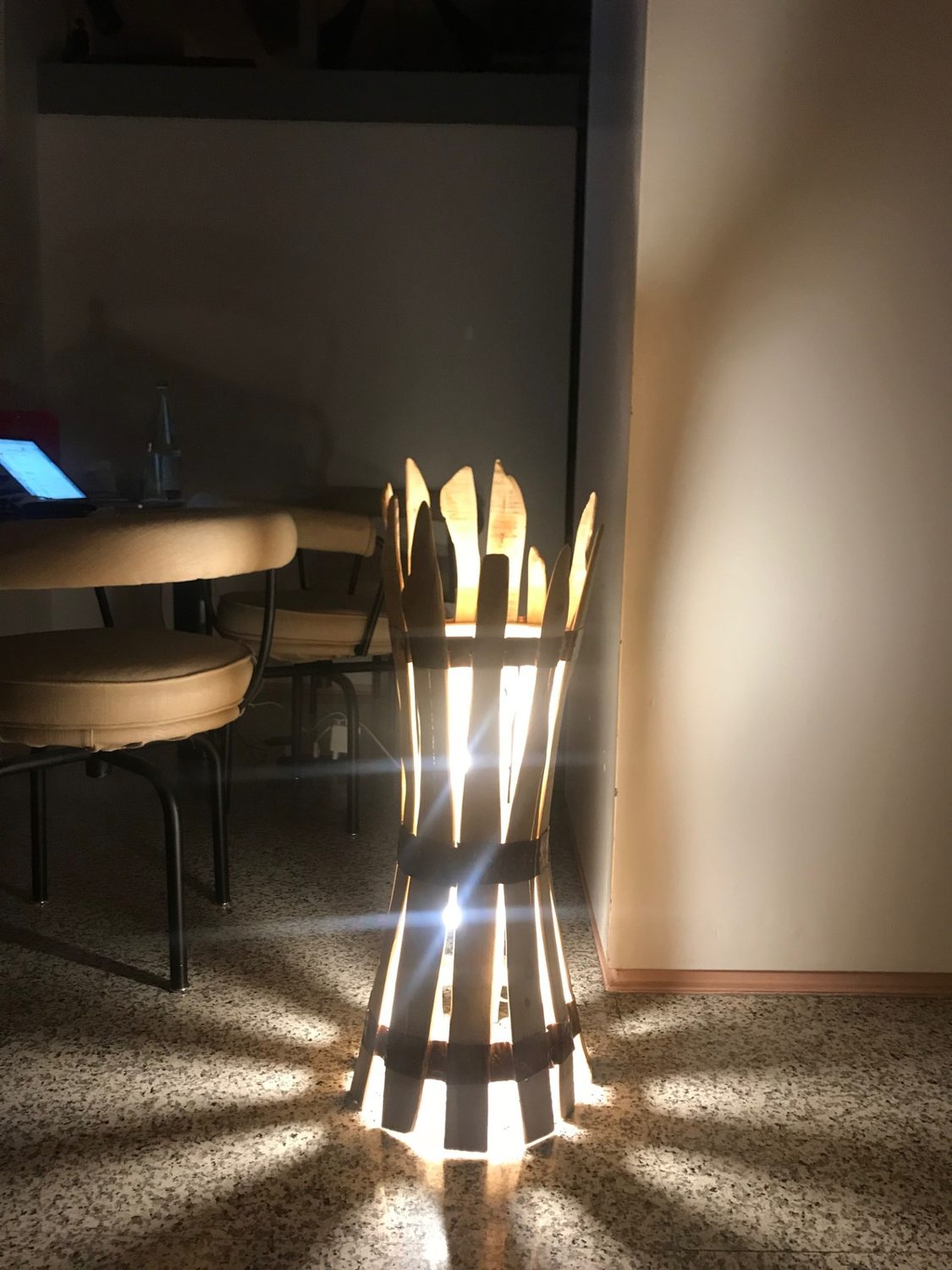 La lampada in ginepro accesa in una stanza buia, accanto a un tavolo