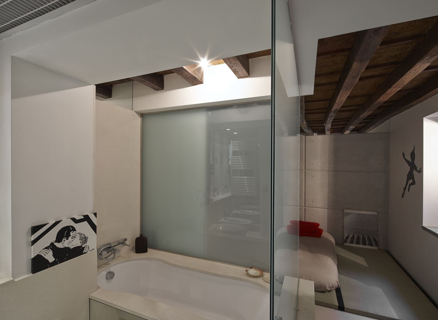 Il tunnel di vetro: la vasca in primo piano, oltre il vetro la camera con il letto basso