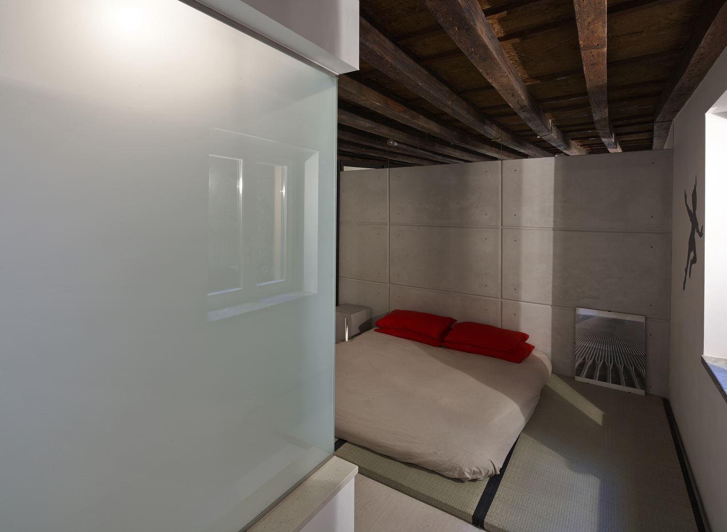 La camera da letto con il letto basso alla giapponese e la parete in cemento