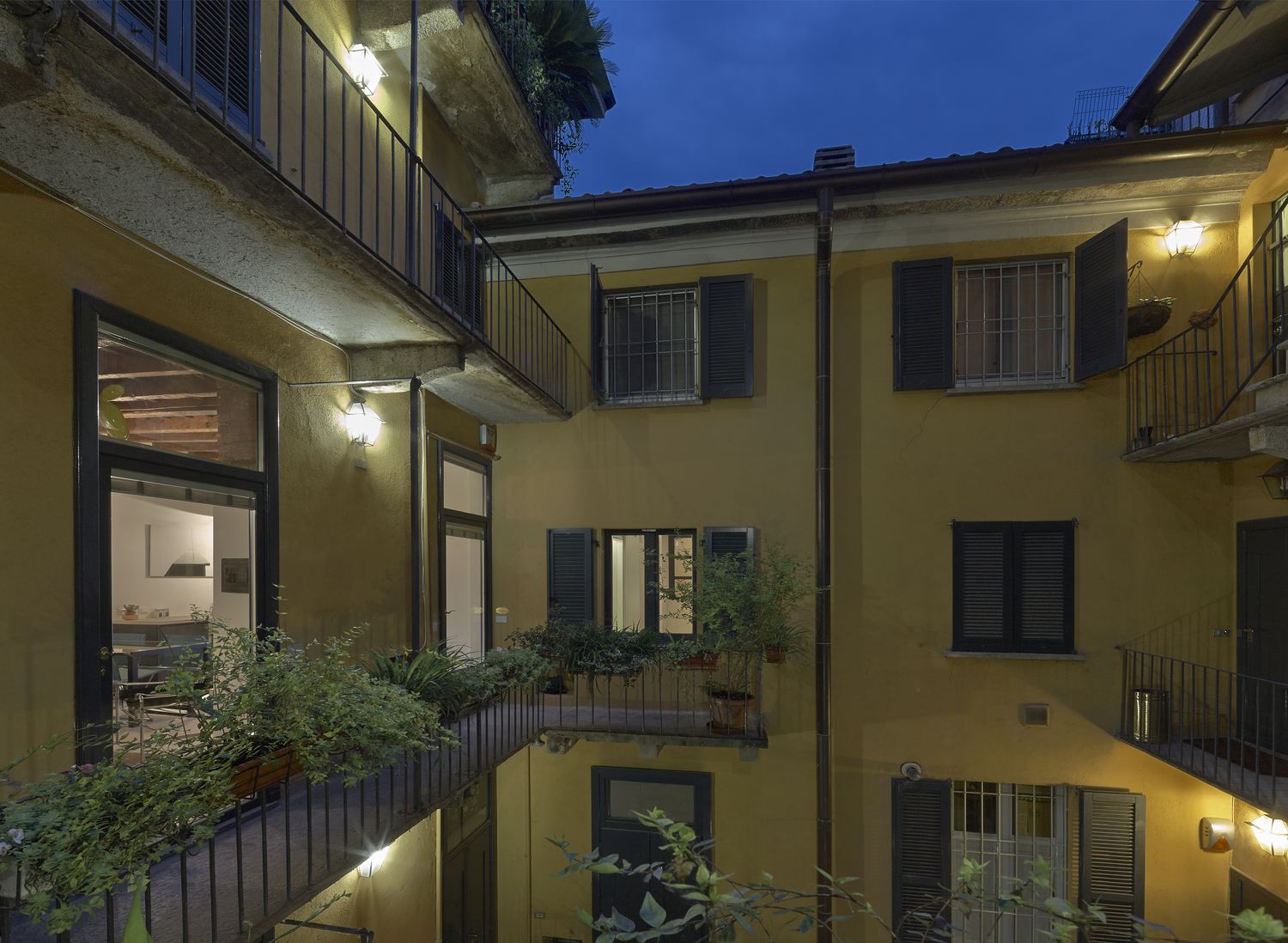 Il cortile del palazzo all'ora blu, con le facciate gialle e le finestre accese