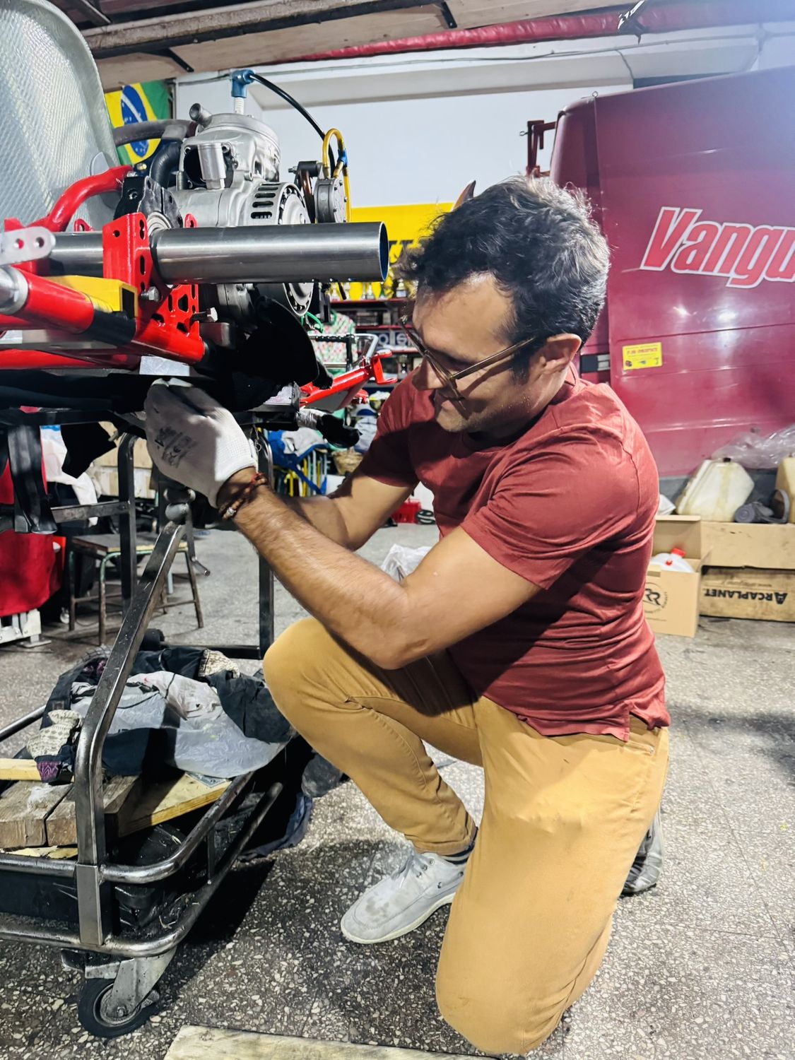 Matteo Gardino accovacciato accanto al kart in officina, mentre lavora all'avantreno