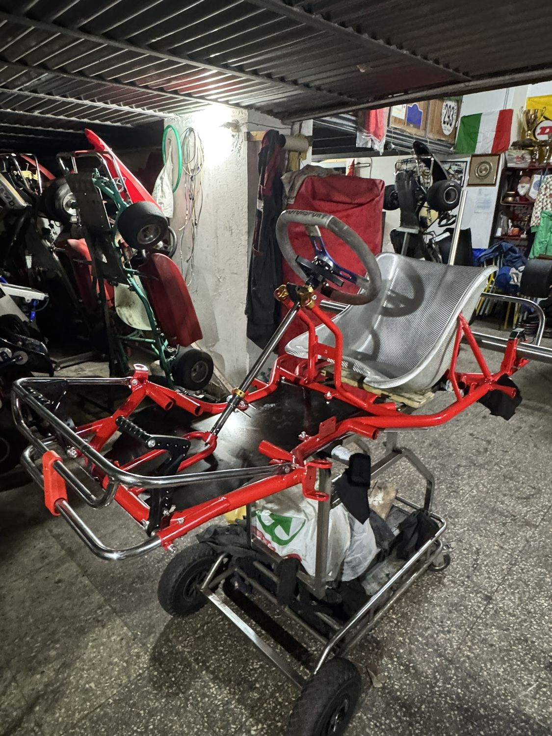 Il kart montato in officina senza carene: telaio rosso, sedile, motore KZ 125 e scarico al loro posto