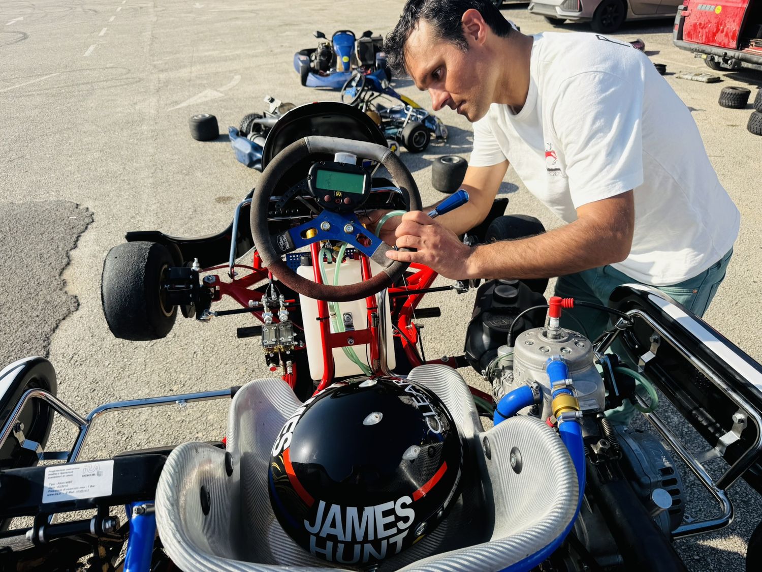 Matteo Gardino chino sul kart nel paddock, con il casco nero appoggiato sul sedile