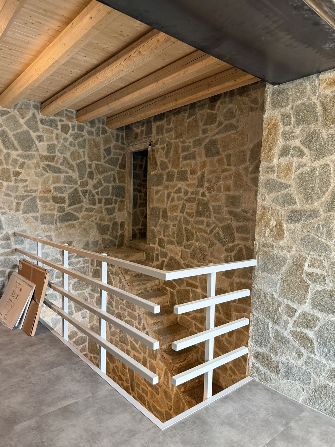 Settembre 2026: la ringhiera bianca contro il muro di pietra del nevaio, vista dal soggiorno