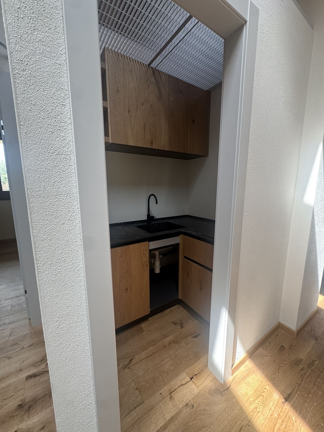 La cucina piccola del piano primo vista dall'apertura: ante in rovere, piano in pietra scura, pavimento in rovere