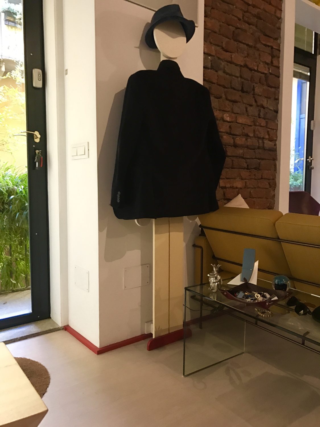 Lo stesso Omino con un cappotto nero appeso e un cappello sulla testa