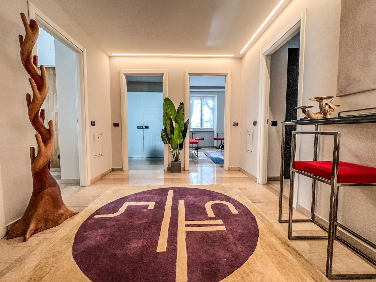 Corridoio con tappeto tondo, scultura in legno e specchio a tutta parete