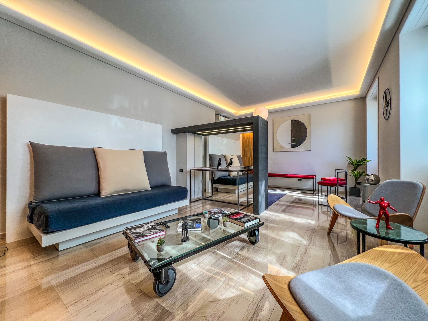 Il soggiorno con la chaise longue, il tavolino su ruote e la parete in legno con la luce radente